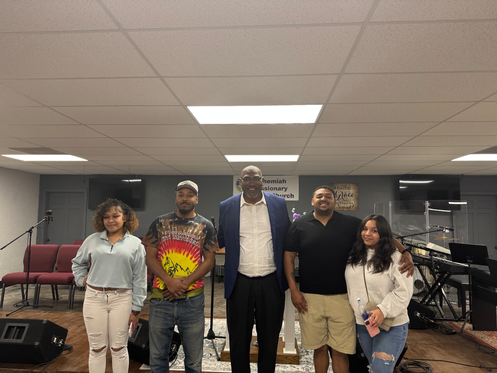A man in a blue blazer with young adults posing at Nehemiah Missionary Baptist Church